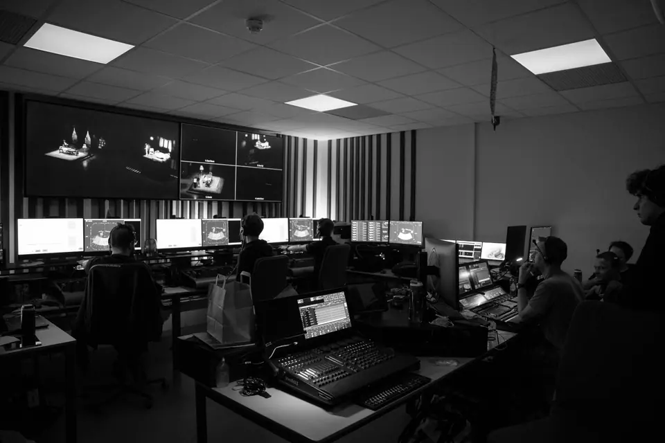 Programmeerruimte van 40-45: grandMA3-tafels, visualisatie op grote schermen en programmeurs met headsets (zwart-wit)