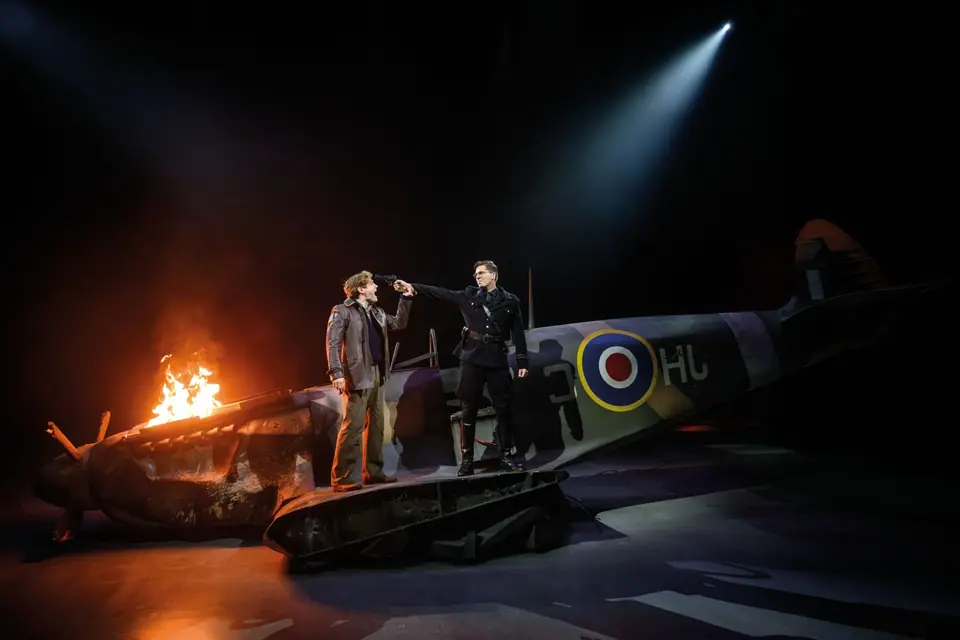 40-45 de musical: neergestorte Spitfire met vuur, officier richt een pistool op een piloot
