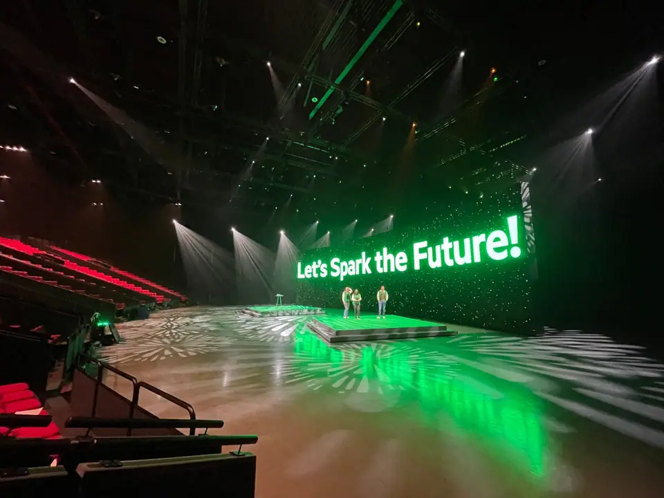 KPN-event in Barneveld: zaal met rode stoelen, beams en gobo-patronen op de vloer, groene LED-wand