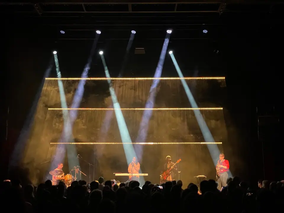 Rewire Festival 2026: witte beams schuin over een gouden achtergrond met lijnen van licht