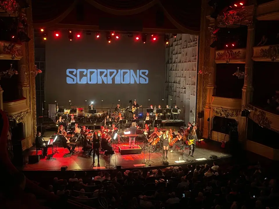 Rock the Opera: orkest in rood licht in een historisch operahuis, het Scorpions-logo op het doek