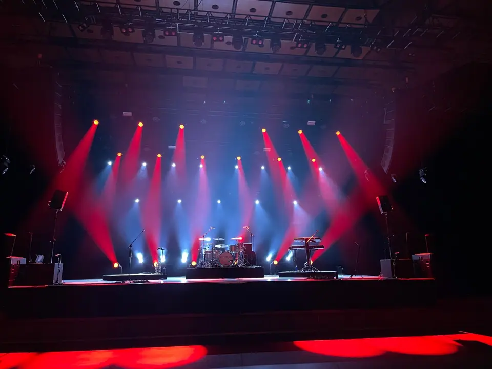 Leeg podium in de Grote Zaal van De Oosterpoort met rode en witte lichtbundels, drumstel van Wet Wet Wet